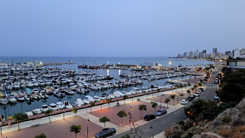 Elevated twilight view of boats docked at El Campello marina and the coastal promenade leading to the beach in Costa Blanca.