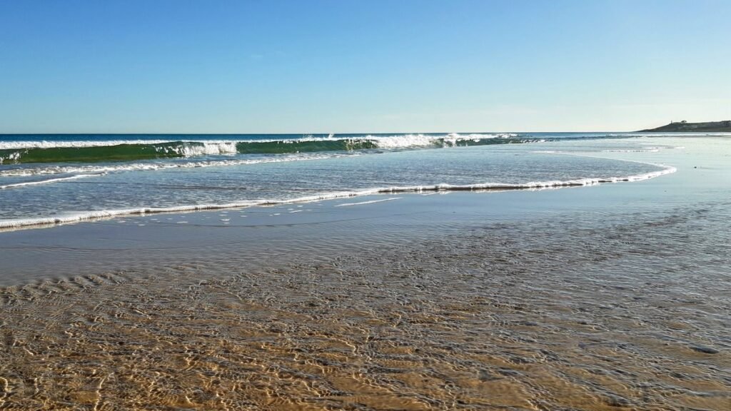Shoreline perspective showing clear transparent waters and gentle waves at Playa de San Juan beach in Alicante